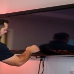 Homeowner carefully dusting a TV cabinet to ensure proper ventilation and performance.